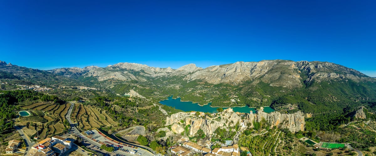 A mountainous landscape with a lake, terraced fields, and a castle.