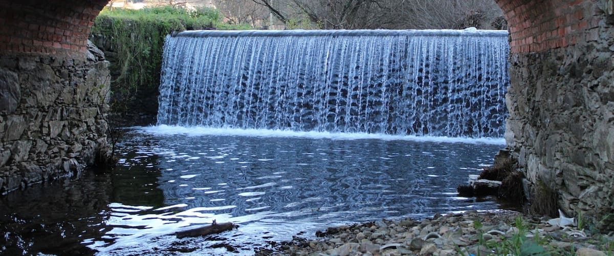 A stone bridge arching over a cascading waterfall.