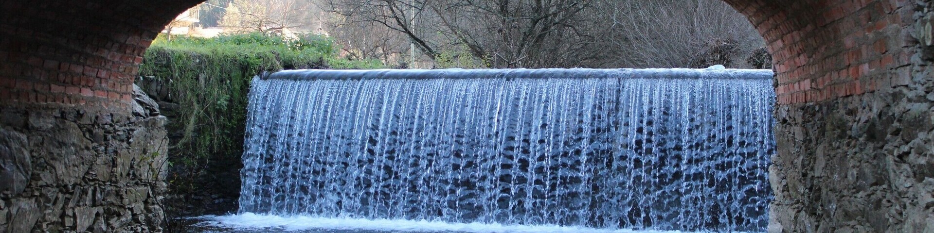A stone bridge arching over a cascading waterfall.