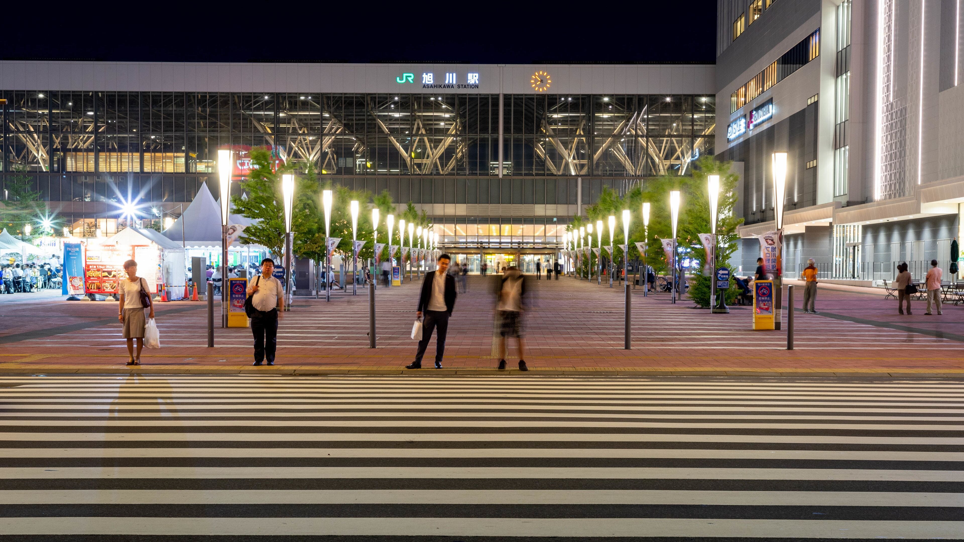 A modern train station with a large glass facade and a clock tower.