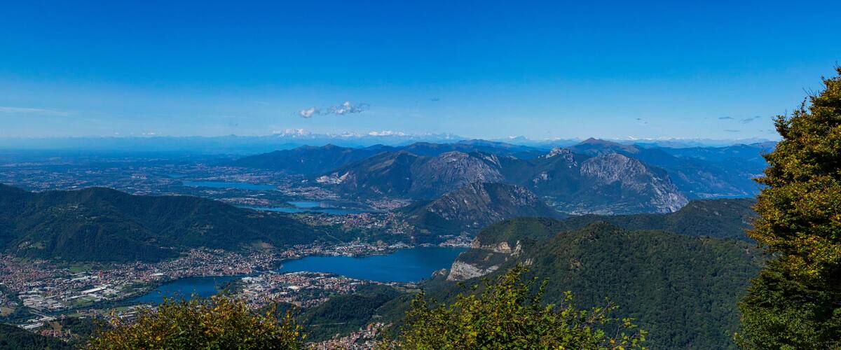 A mountainous landscape with a town, a lake, and distant snow-capped peaks.