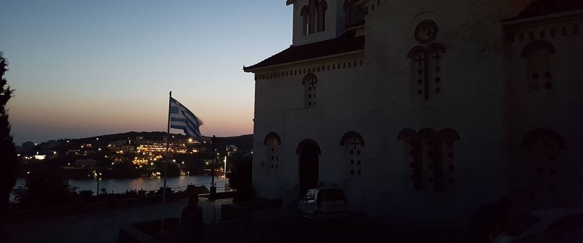 A church with a cross on top, a flag, and a crescent moon in the sky.