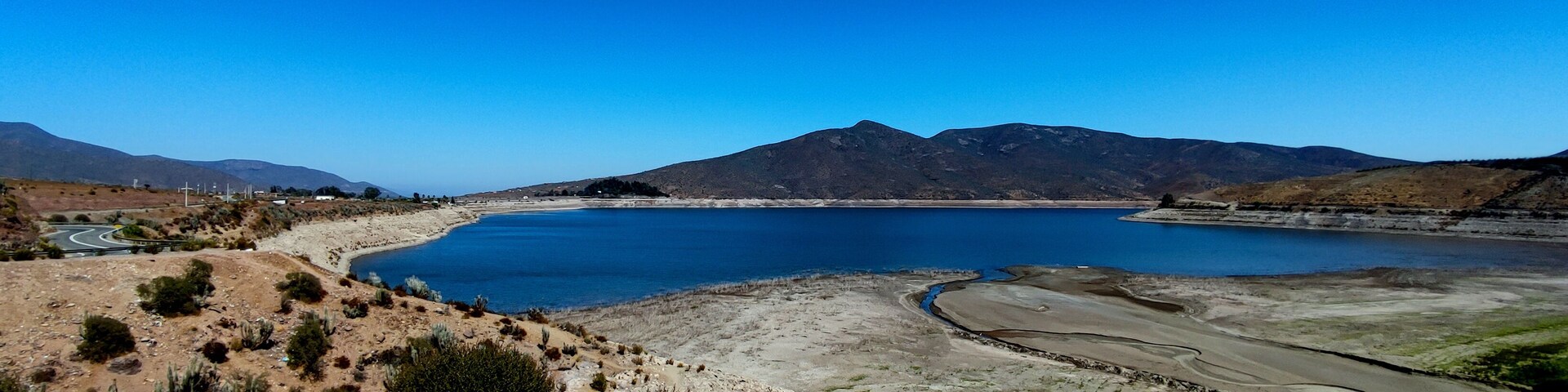 Un lago grande rodeado de montañas y una carretera serpenteante.