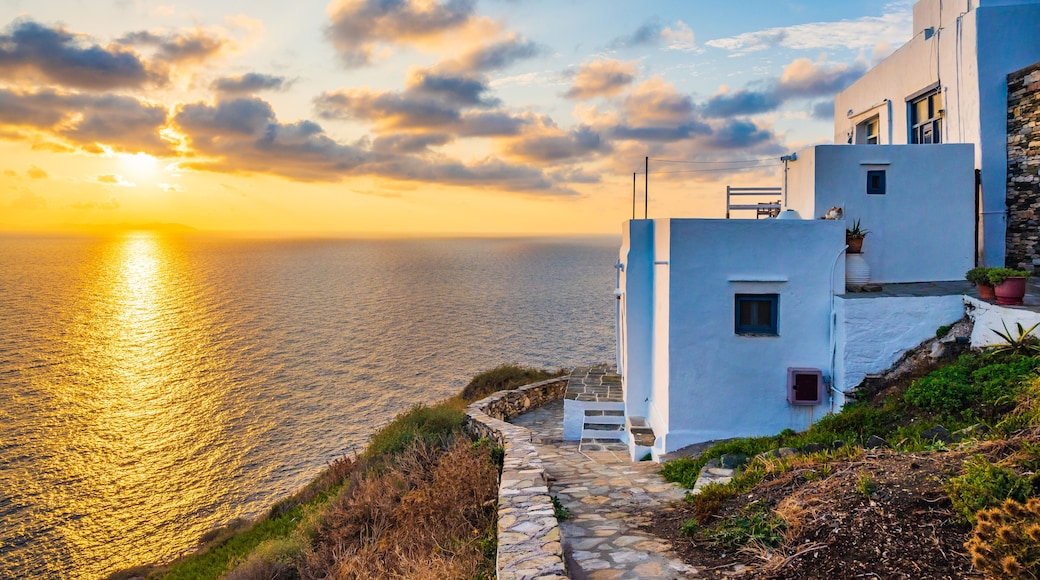Sunrise over rocky coast of Sifnos island with typical white houses in foreground in Kastro village, Cyclades, Greece