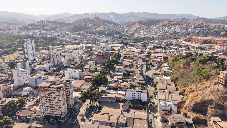 A cityscape with a prominent high-rise building, a dense urban area, and a mountainous backdrop.