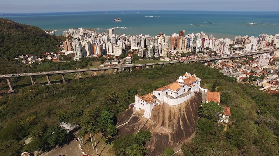 A coastal cityscape with a prominent white church on a cliff overlooking the sea.