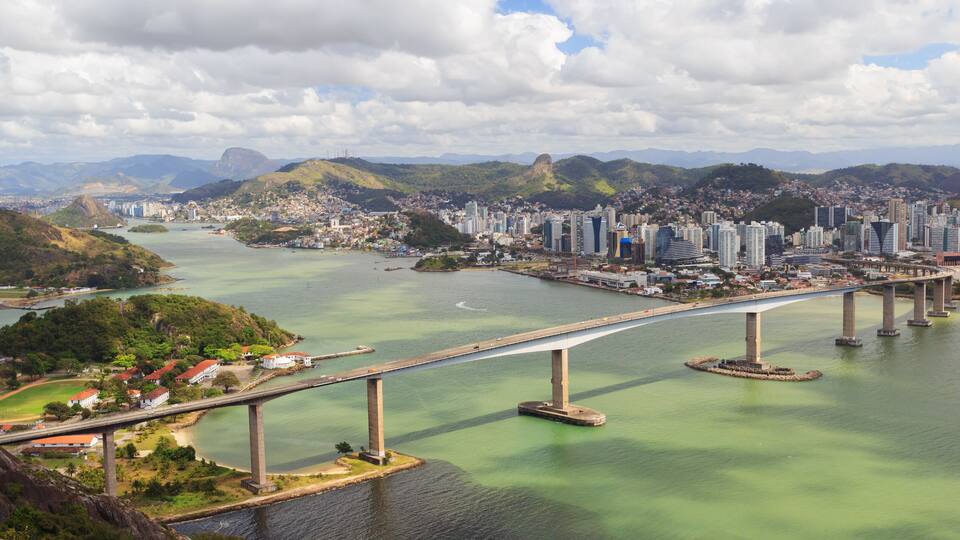 A bridge spanning a river with a cityscape in the background.