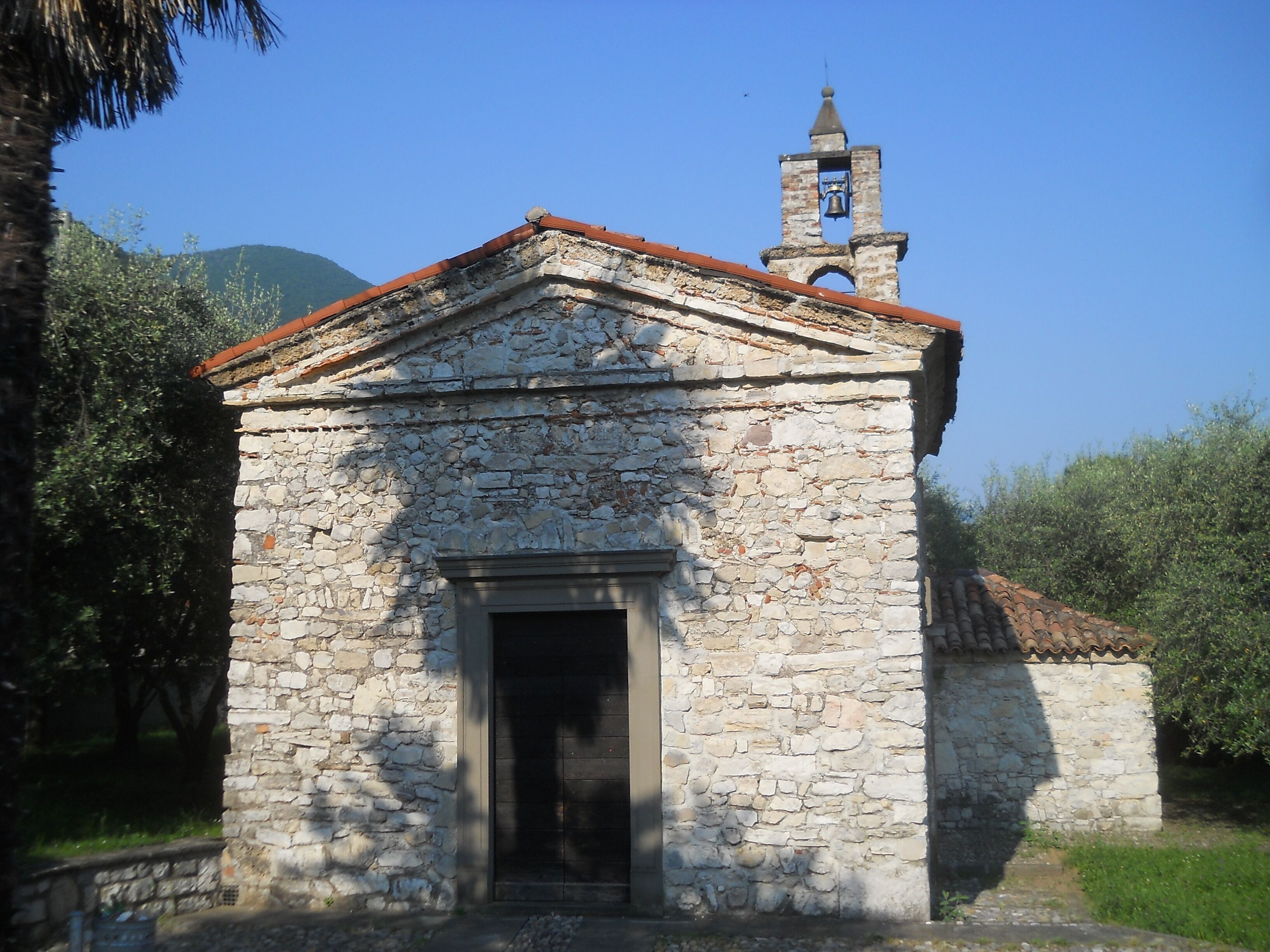 A small stone church with a bell tower and a red-tiled roof.