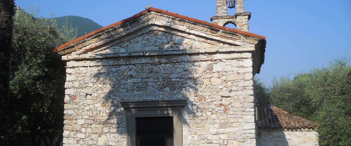A small stone church with a bell tower and a red-tiled roof.