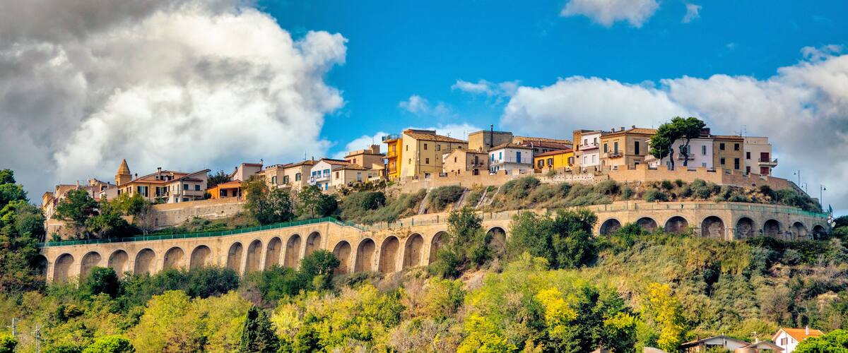 A hillside town with historic buildings and a stone bridge.