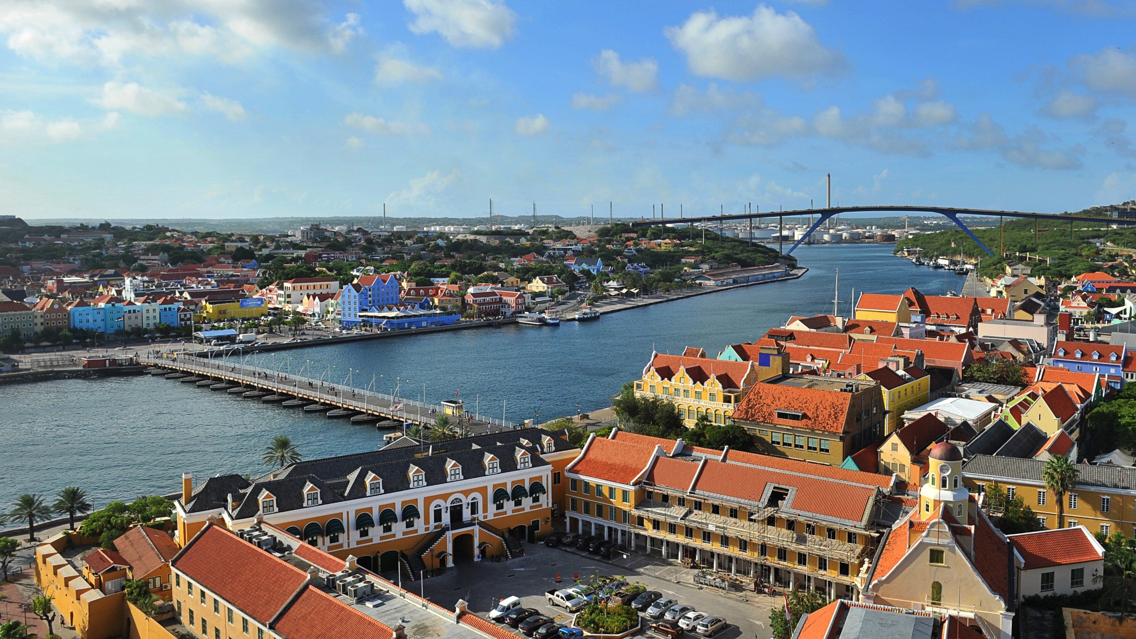 Un pueblo costero con edificios coloridos, un puente y un puerto deportivo.