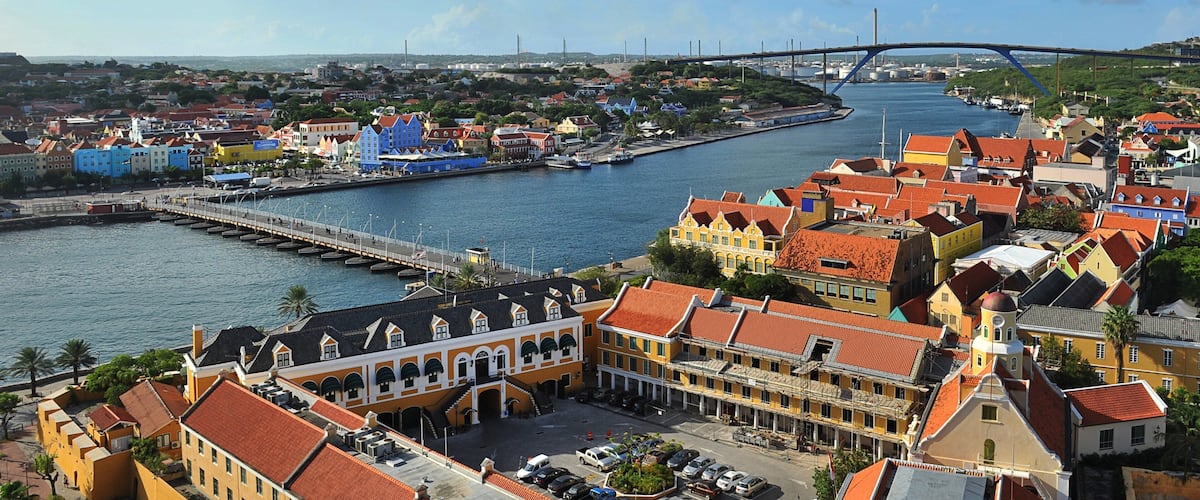 Une ville côtière aux bâtiments aux couleurs vives, avec un pont et un port de plaisance.
