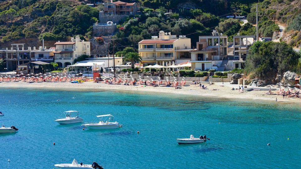 A coastal town with a beach, boats, and buildings.