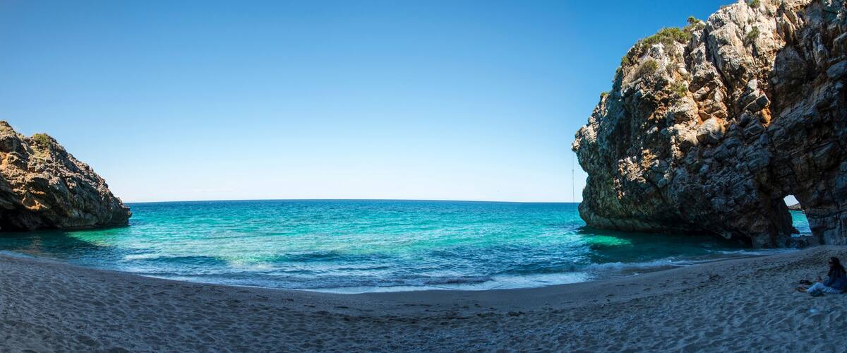 A beach with rocky cliffs and clear turquoise water.