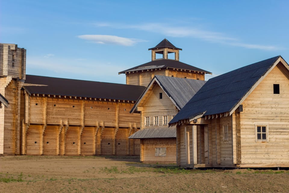 A wooden building complex with a central tower and smaller structures.