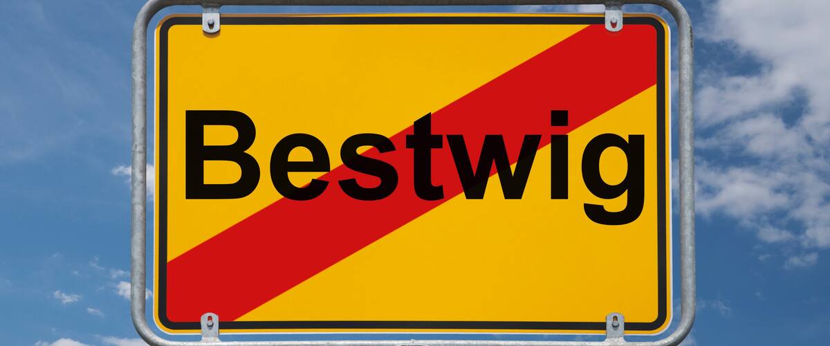 A road sign with the word "Bestwig" against a blue sky with clouds.