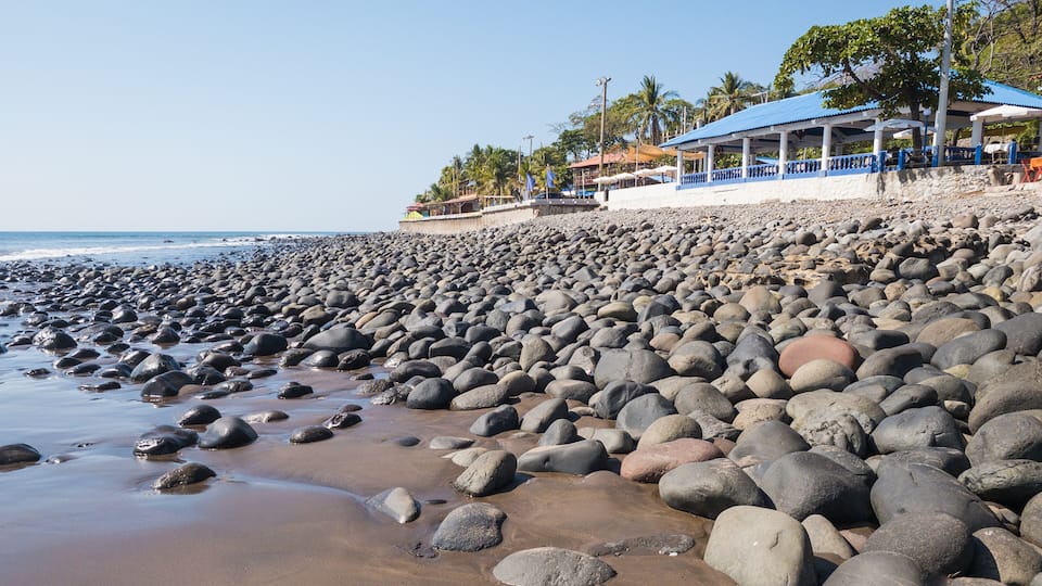 A rocky beach with a building in the background.