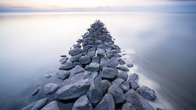 A long, narrow stone pier extending into calm water.