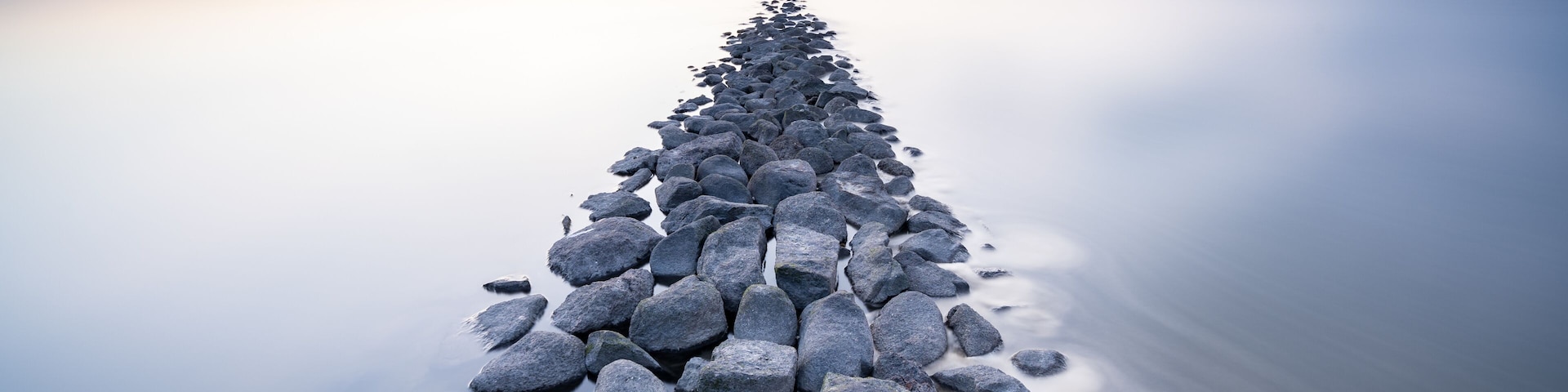A long, narrow stone pier extending into calm water.