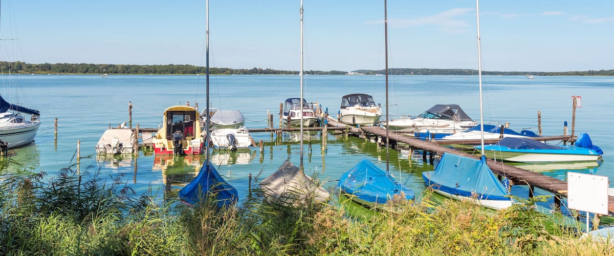 A calm lake with several boats docked at a pier.