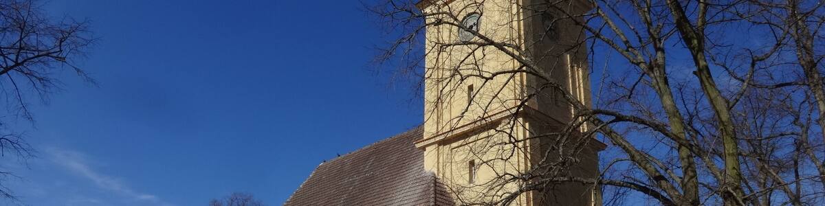Eine Kirche mit einem hohen Turm und Rundbogenfenstern.