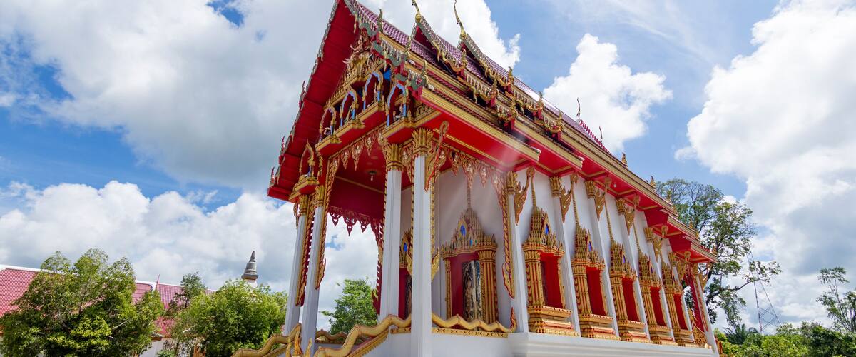 A temple with a red and gold roof, white walls, and intricate decorations.