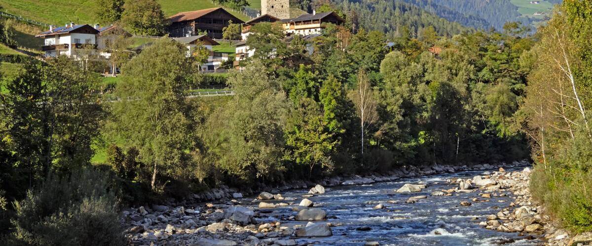 A mountain village with houses, a tower, and a river.