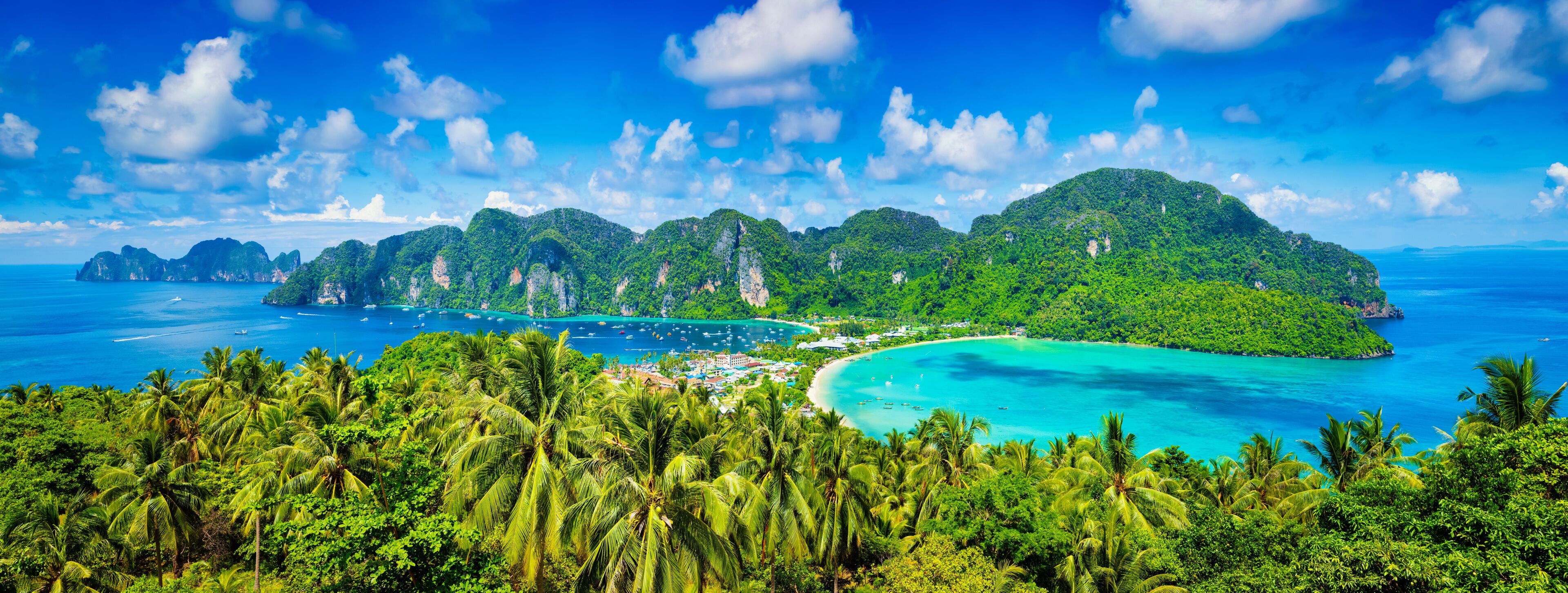 A tropical island with lush greenery, clear turquoise waters, and a small town by the beach.