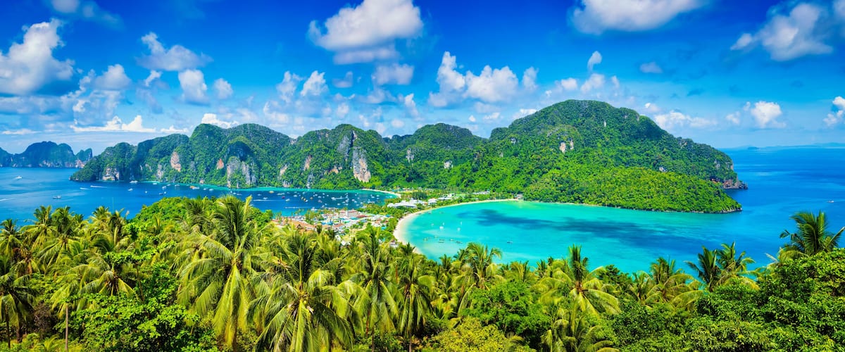 A tropical island with lush greenery, clear turquoise waters, and a small town by the beach.