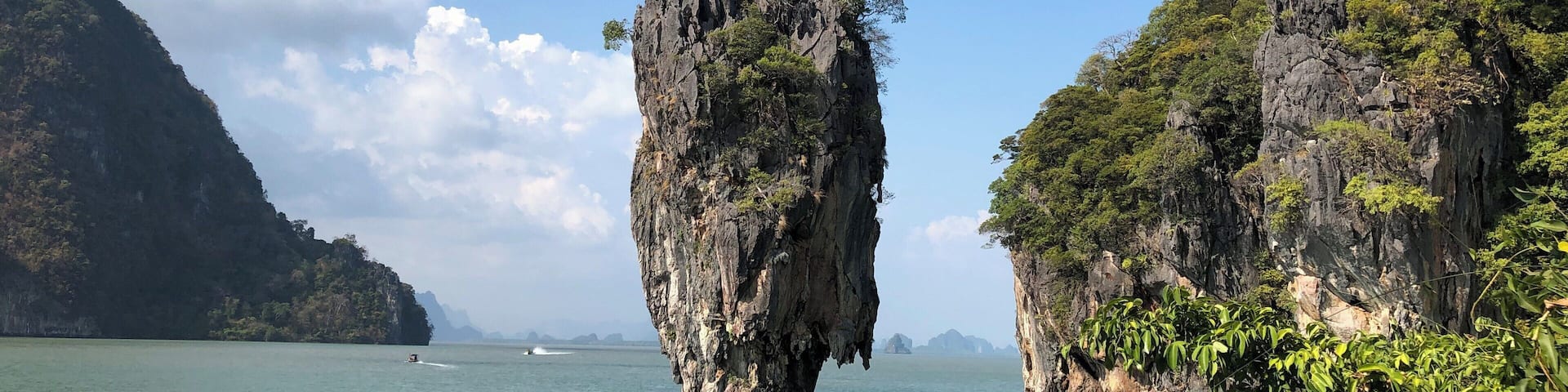 A karst landscape with limestone pillars and a calm sea.