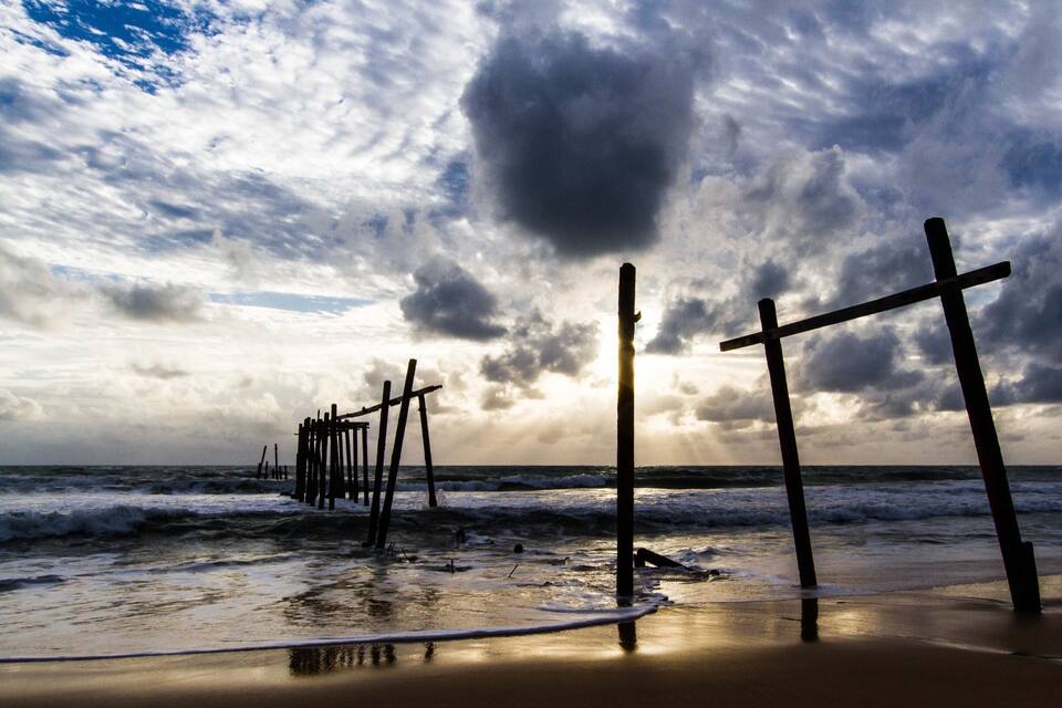 A beach with wooden posts and waves.