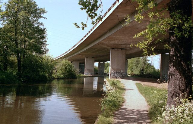 A concrete bridge over a river with a walking path beside it.
