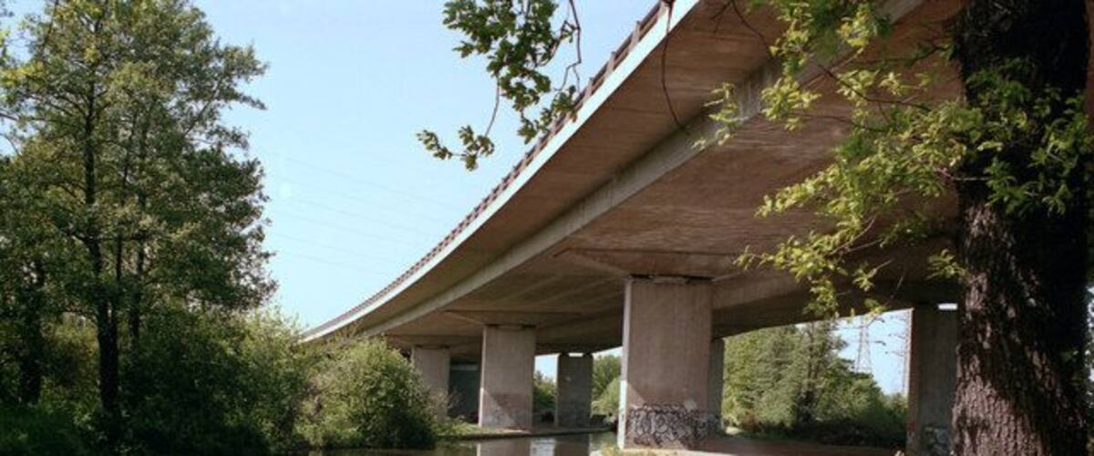 A concrete bridge over a river with a walking path beside it.