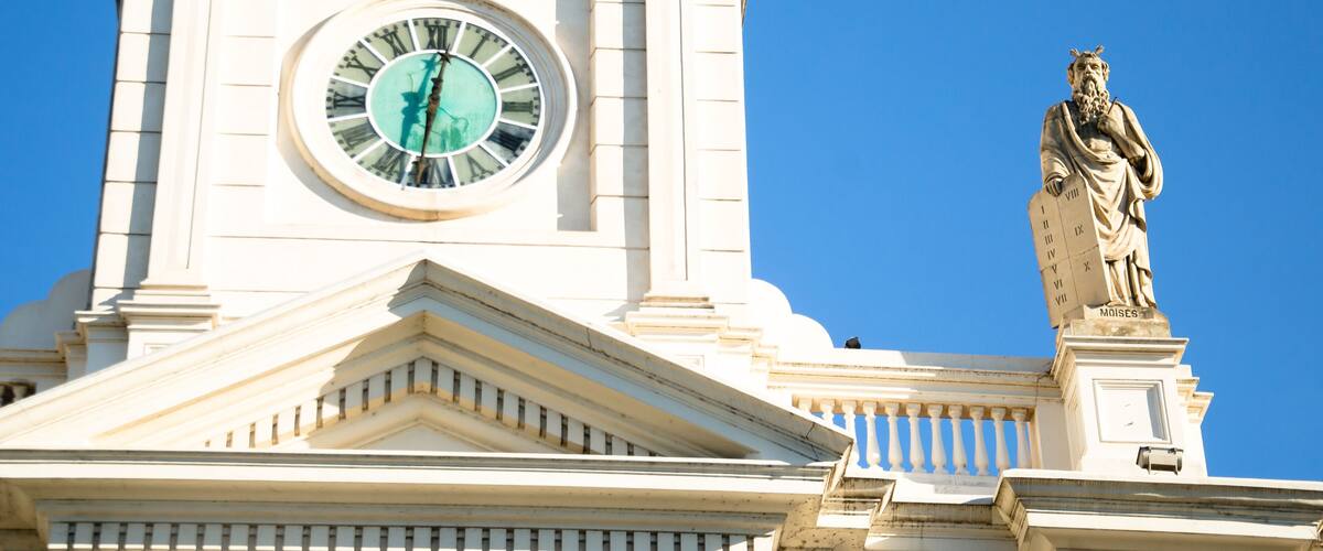 A clock tower with a statue on top.