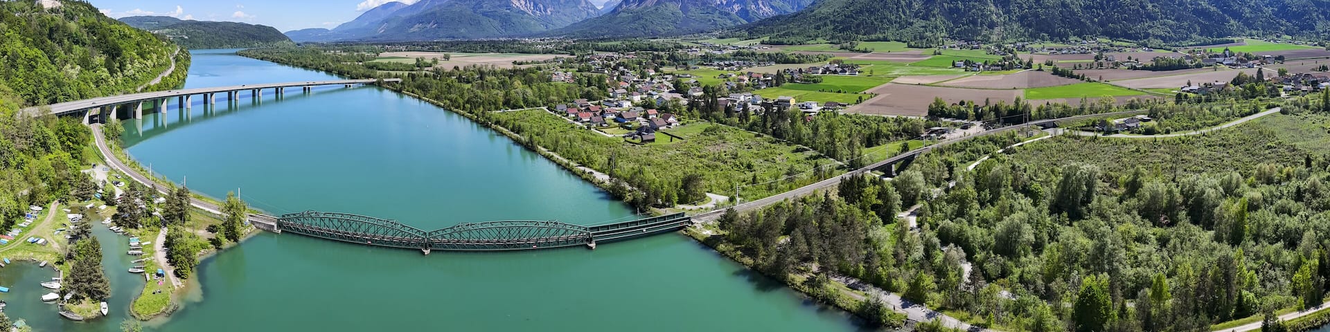 A river with a bridge, a town, and mountains in the background.
