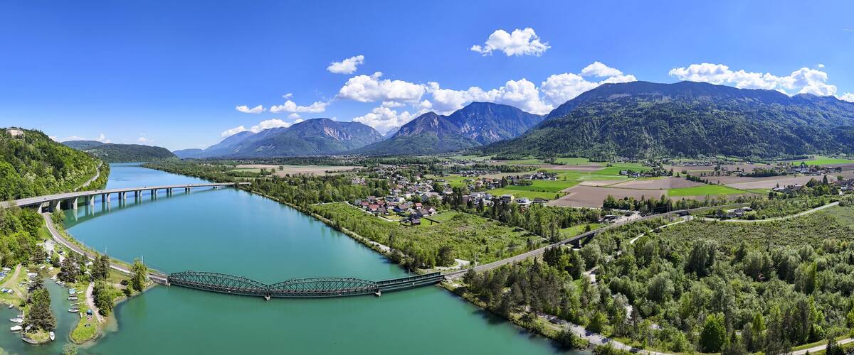 A river with a bridge, a town, and mountains in the background.