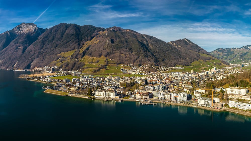 A coastal town with a mountain backdrop, a harbor, and a clear sky.