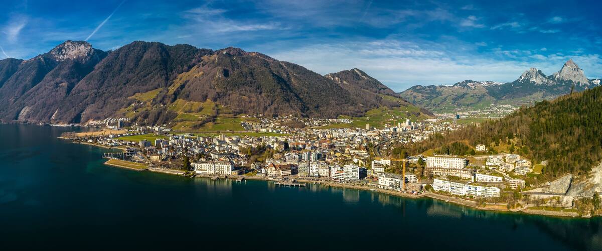 A coastal town with a mountain backdrop, a harbor, and a clear sky.