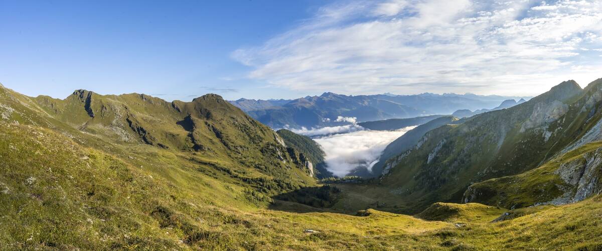 A mountainous landscape with a valley, rugged peaks, and a clear sky.