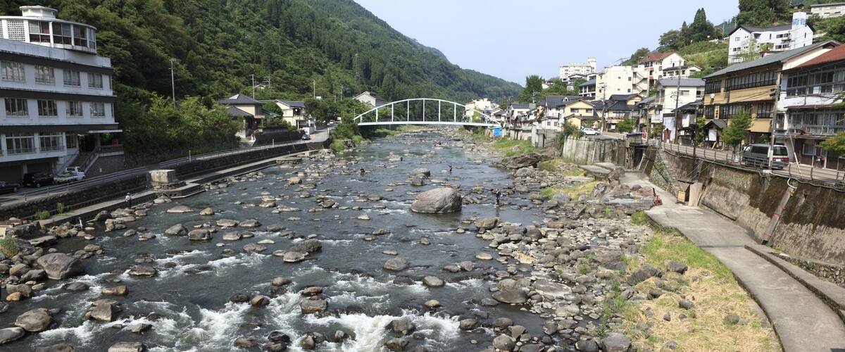 A river with rocks, a bridge, and houses along the riverbank.