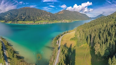Un lago rodeado de colinas boscosas y una carretera sinuosa.