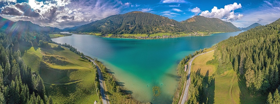 Un lago rodeado de colinas boscosas y una carretera sinuosa.
