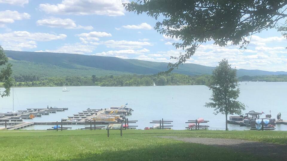 A lake with a dock, boats, and a sailboat.