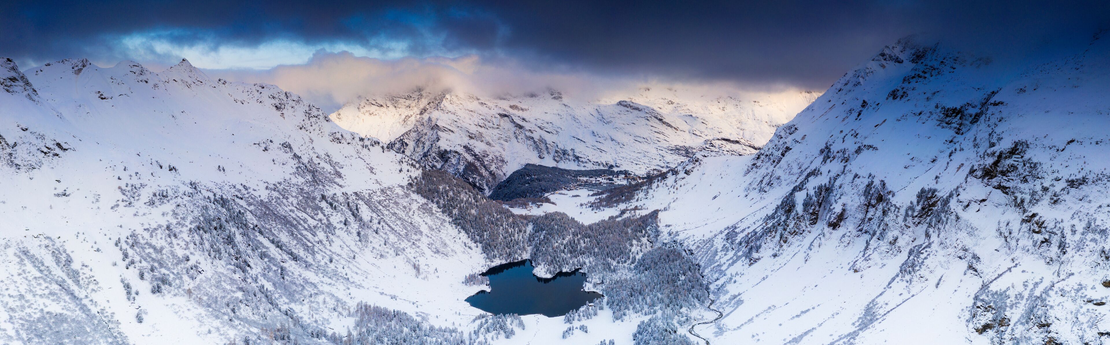 Aerial panoramic of Lake Cavloc and snowy woods, Bregaglia Valley, Engadine, canton of Graubunden, Switzerland