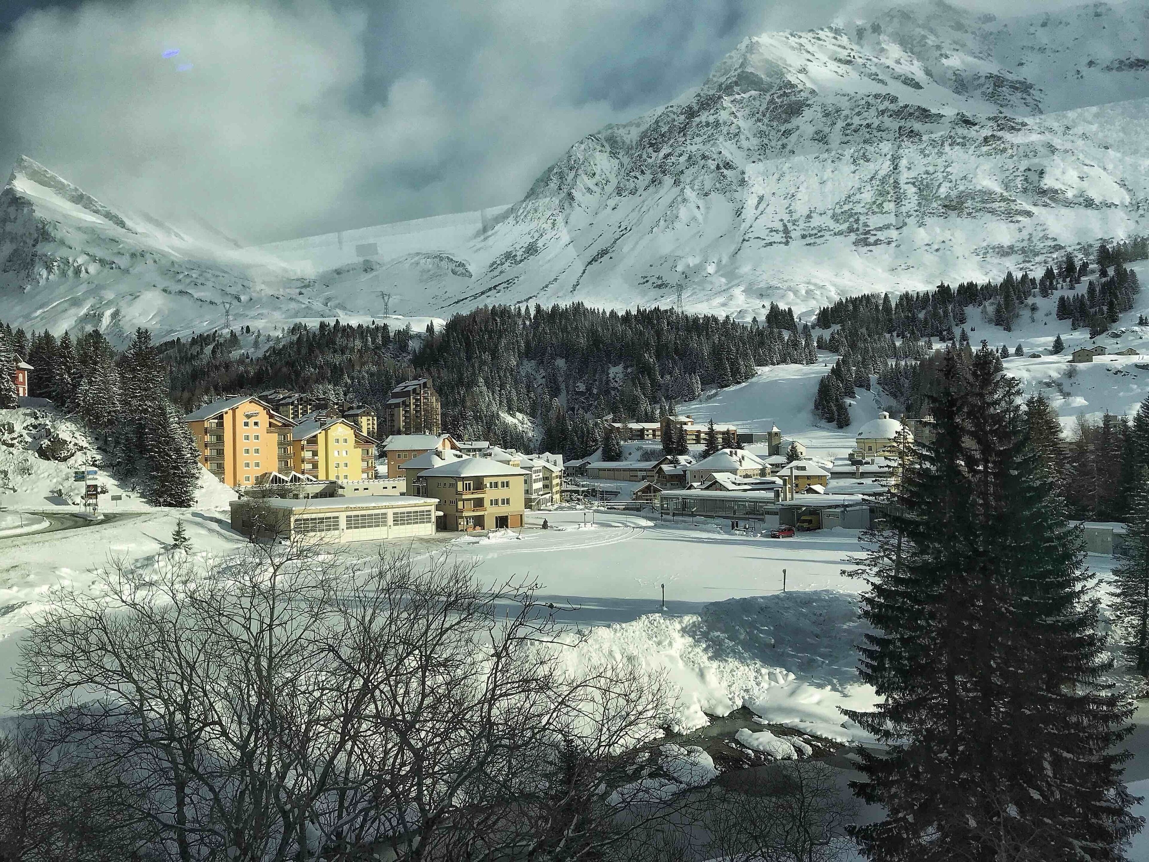 A snow-covered mountain town with buildings and a ski resort.