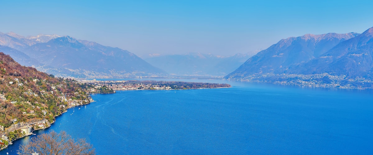 A lake surrounded by mountains with a town on the left side.
