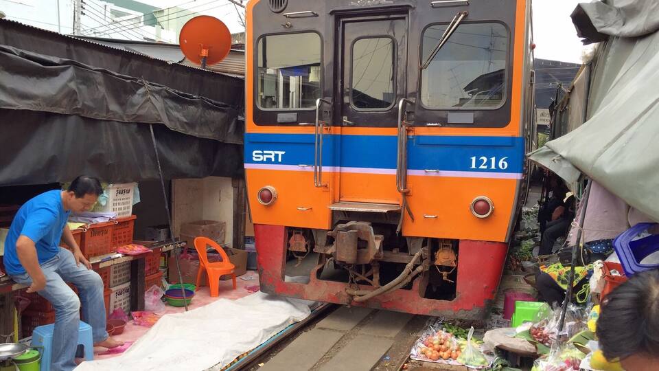A train with the number 1216 parked in a market area.