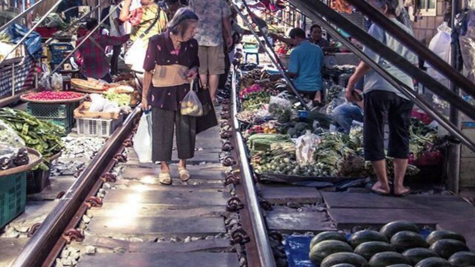 A market with vendors selling fruits and vegetables on a railway track.