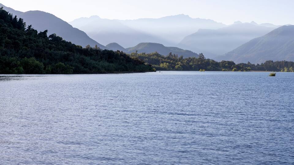 A calm lake with mountains in the background.