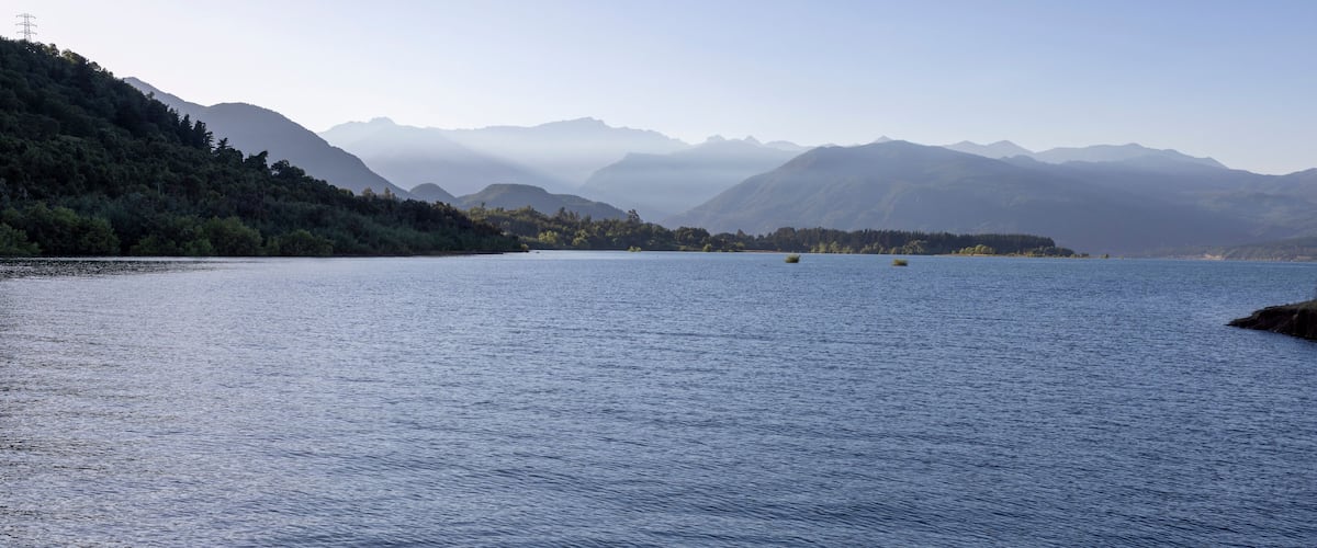 A calm lake surrounded by mountains and dense forest.
